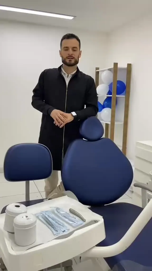 Dentista da Odonto Prime ao lado da cadeira odontológica azul no consultório em Mauá